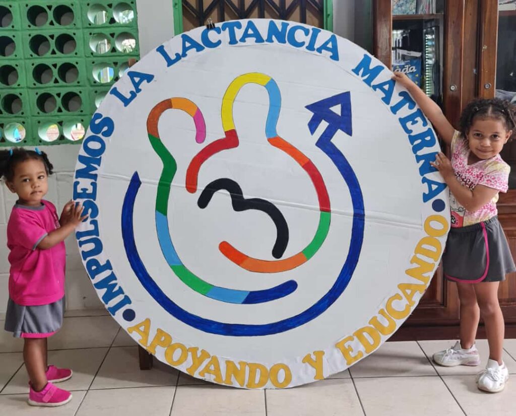 En la imagen se muestra cartel alusivo a la semana de la lactancia materna, sujetado por dos niños