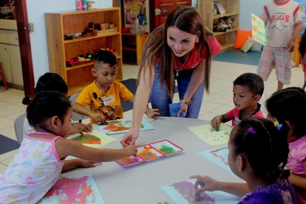 Fotografia de educadora explicando a 6 niños en una mesa