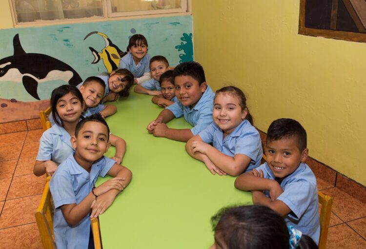 En la imagen se aprecian diez niños compartiendo en una mesa.